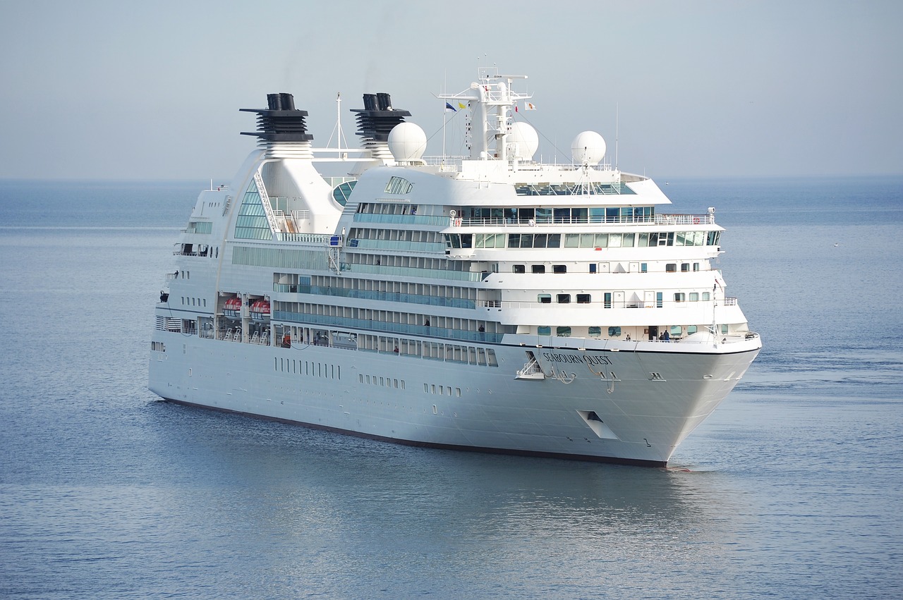 A large white cruise ship sits on calm waters.