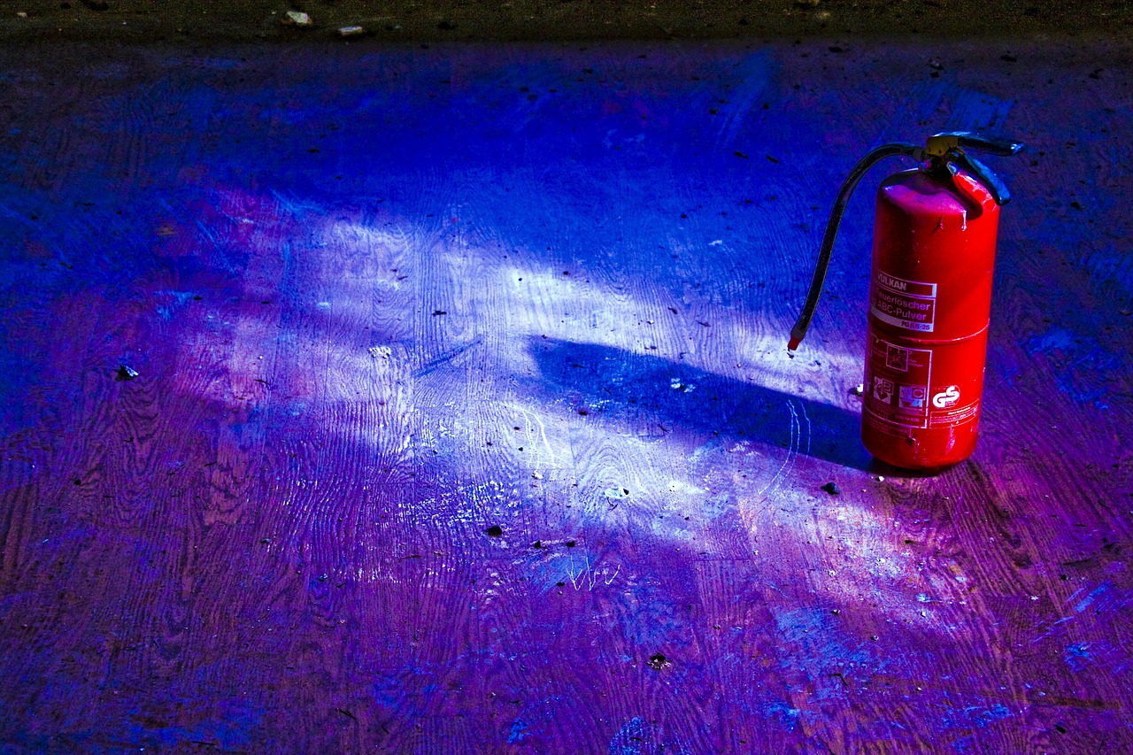 A fire extinguisher sits in shadow on a purple floor.